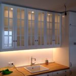 Diese weiße Küche im Landhausstil ist mit ihren beleuchteten Glasfronten an den Oberschränken ein richtiger Blickfang! Das Porzellanwaschbecken sowie die Vollholzarbeitsplatte geben ihr den nötigen Schliff.